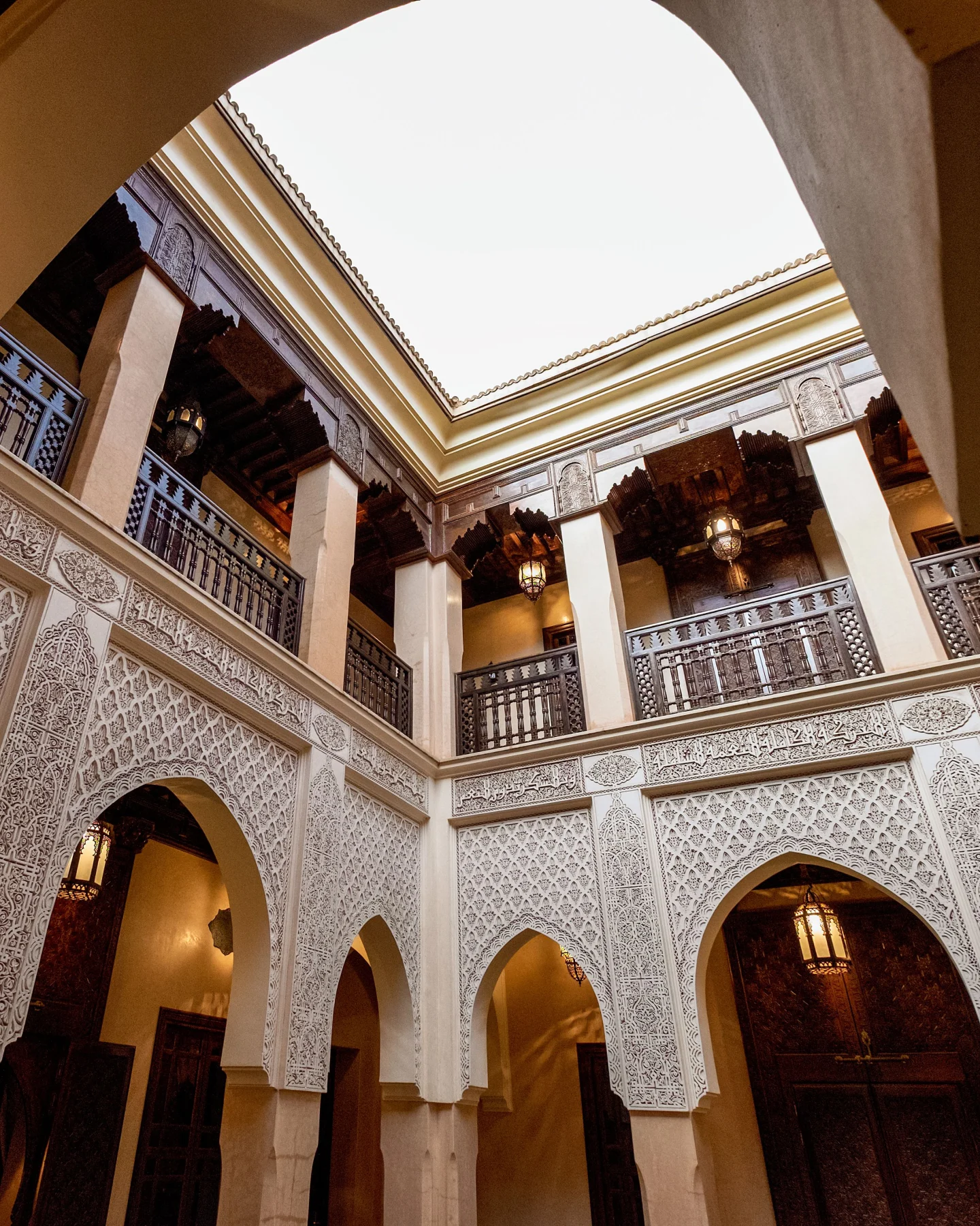Patio intérieur marocain avec arches, bois sculpté et puits de lumière